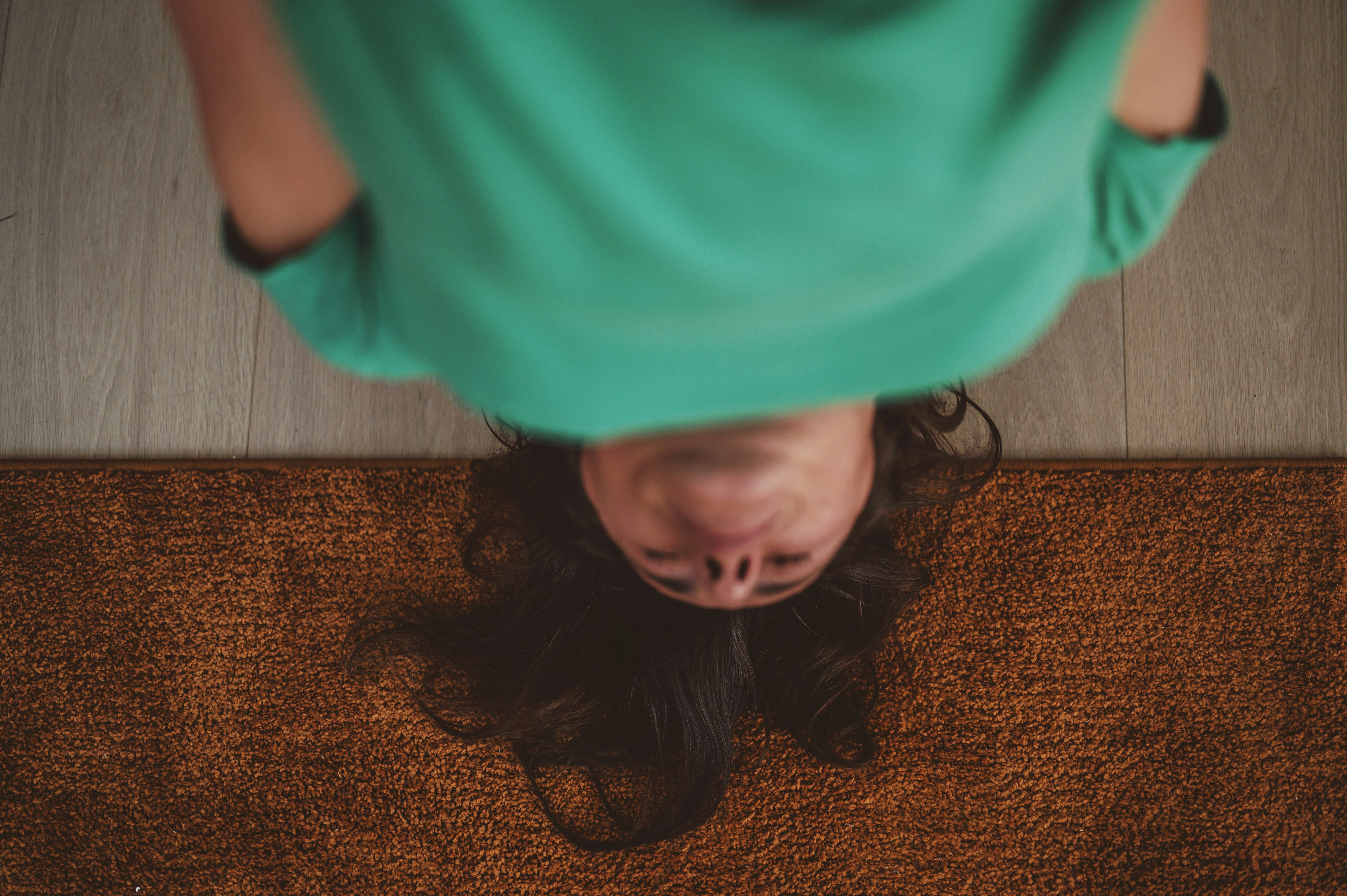 girl in green shirt lying on brown area rug
